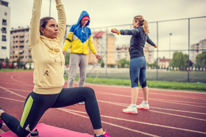 Healthy young friends doing exercises outdoors.They do streching before their workout.