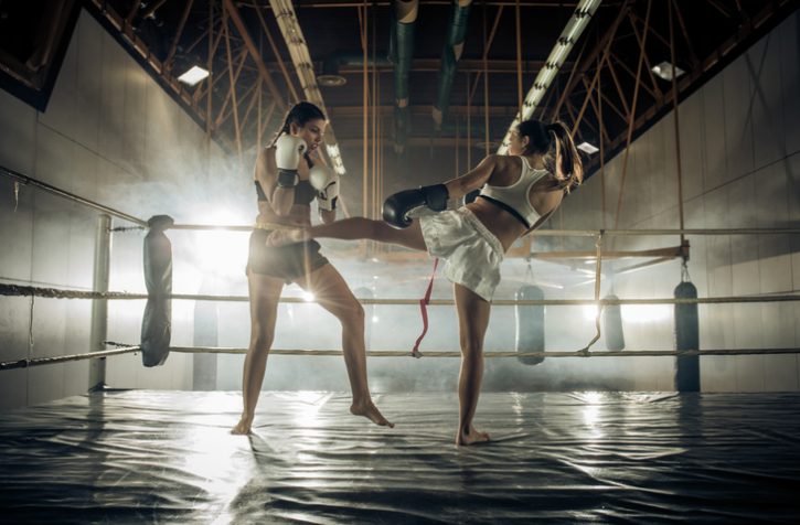 Two determined athletes fighting on a kickboxing training in a ring.