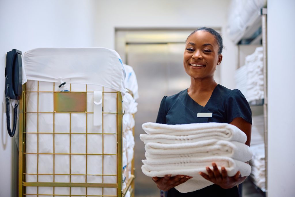 Happy black chambermaid working in a hotel and looking at camera.