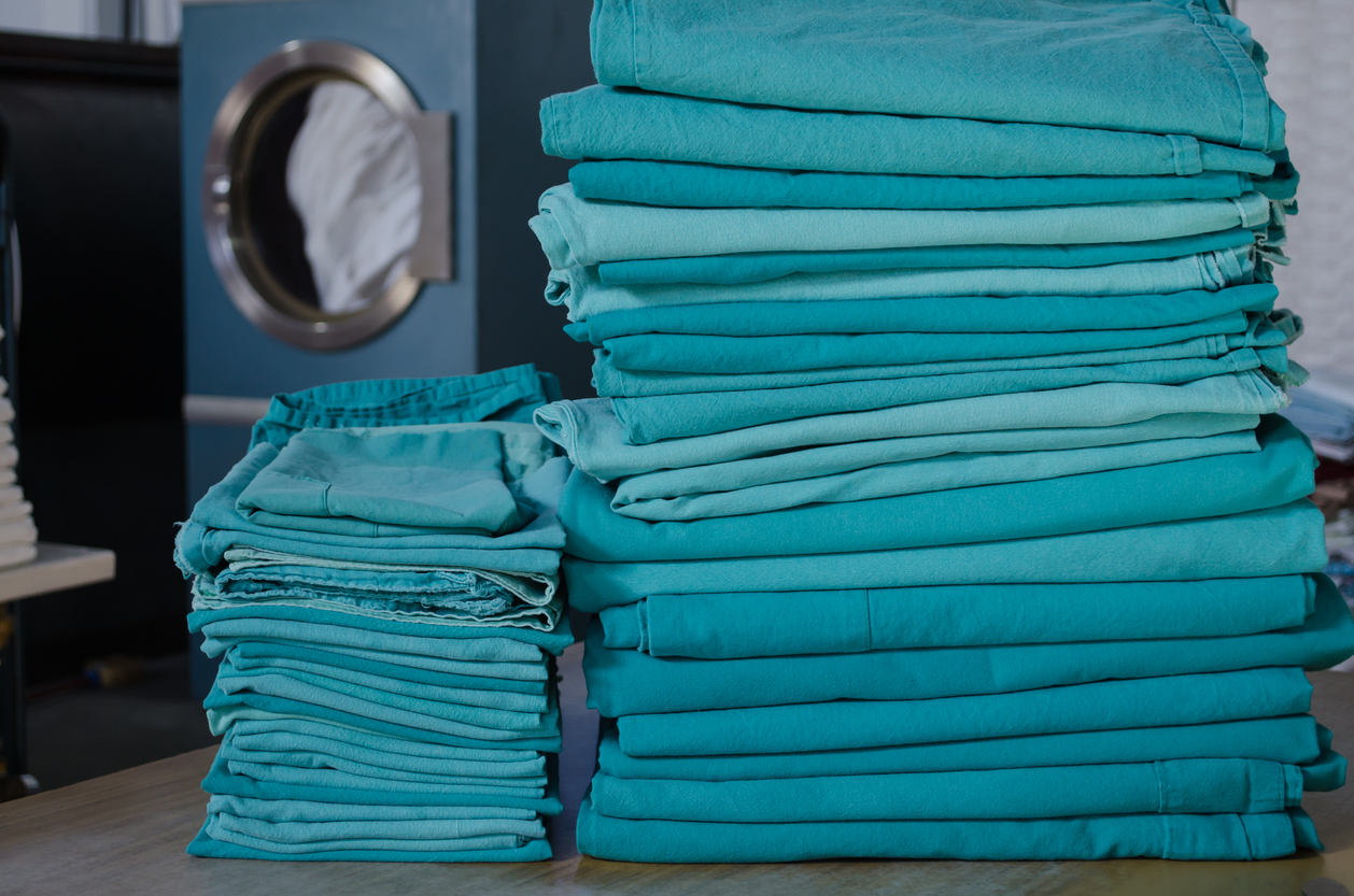 Stack of green surgical clothes in an industrial laundry.