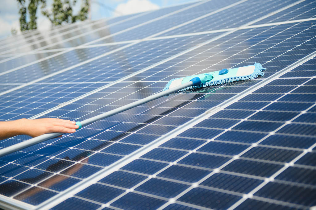 young worker cleaning solar panels.