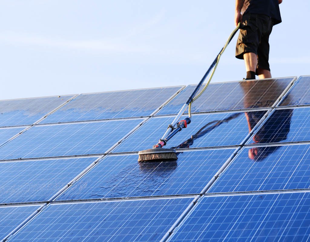 Cleaning solar panels with brush and water