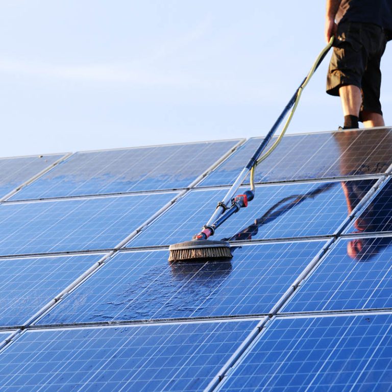 Cleaning solar panels with brush and water